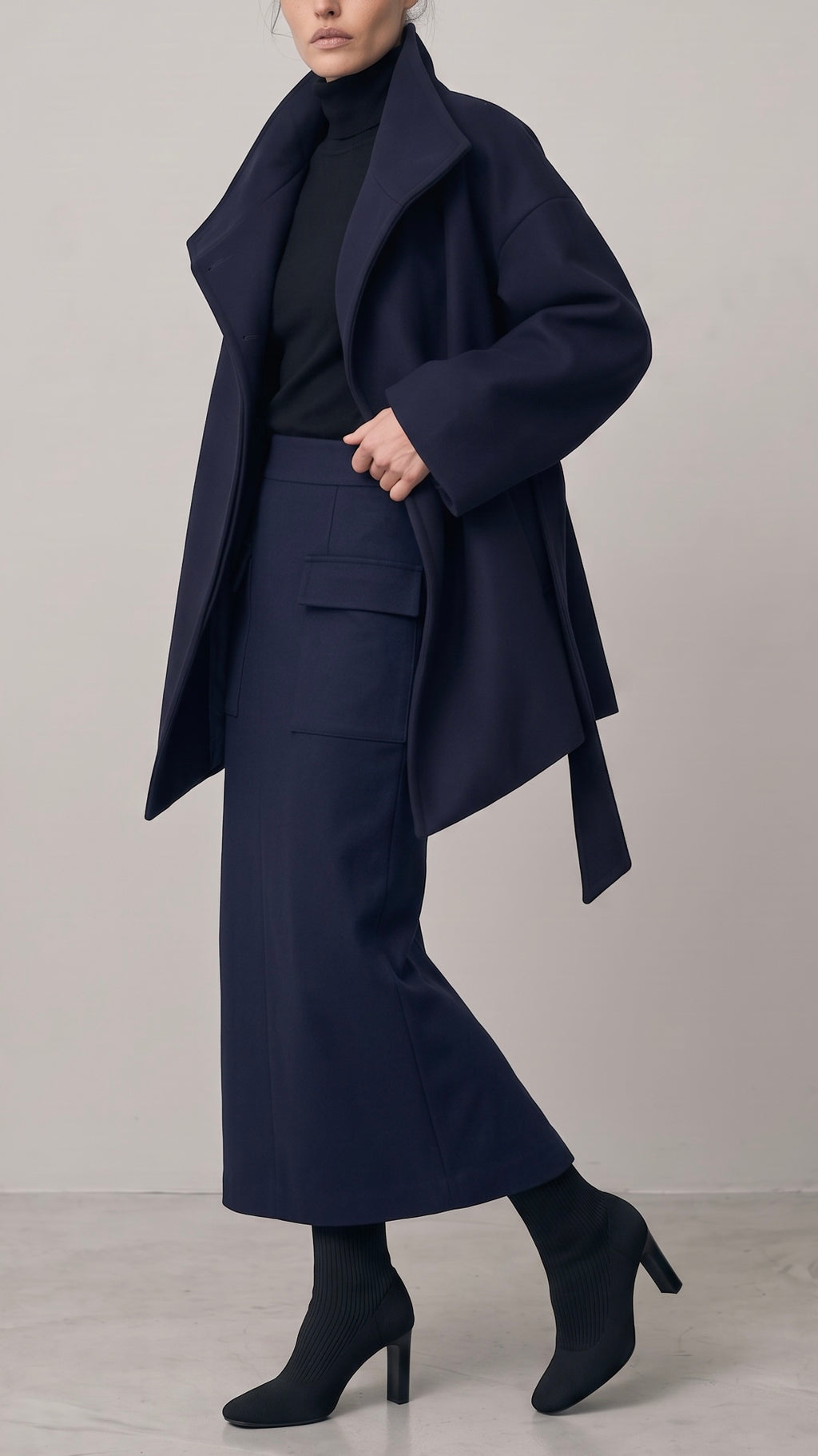 Nocturne Coat, Pillar Skirt and Spine Turtleneck: oversized virgin wool coat with a funnel neck and self-tie belt over a wool midi pencil skirt and buttoned-back turtleneck, made in Italy by The Ethos Studio