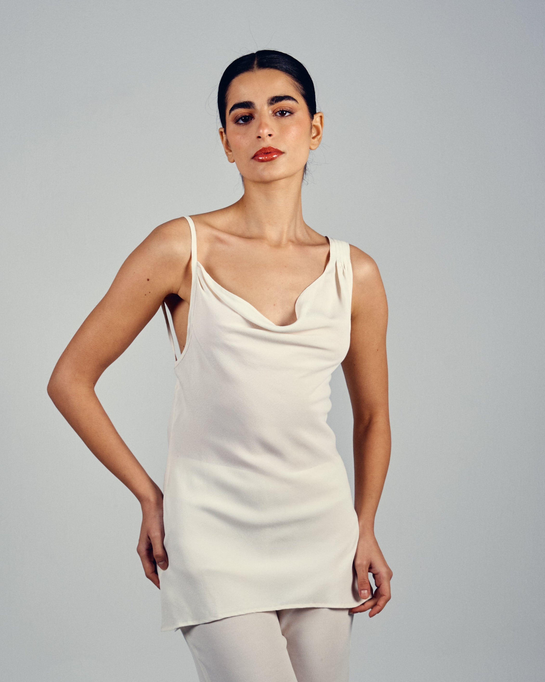 Woman wearing a white sleeveless top on a plain background